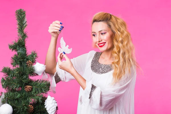 Χριστούγεννα, διακοπές και άνθρωποι έννοια - νέοι ευτυχισμένη γυναίκα ξανθιά διακόσμηση του Χριστουγεννιάτικου δέντρου σε ροζ φόντο — Φωτογραφία Αρχείου