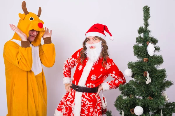 Happy young woman in santa claus hat and man in carnival costume of deer. Fun, holiday, joke and christmas concept — Stock Photo, Image