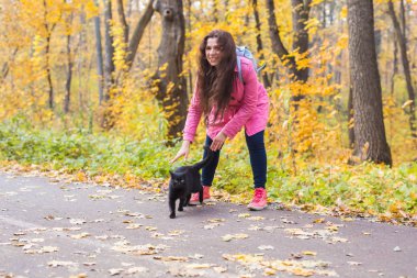Evcil hayvan ve insan kavramı - genç kadın Sonbahar Park kara kedi ile oynarken