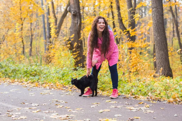 Autumn, pets, people concept - happy woman laughing with the black cat