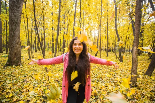 Grappige jongedame gooien van bladeren in de herfst park — Stockfoto