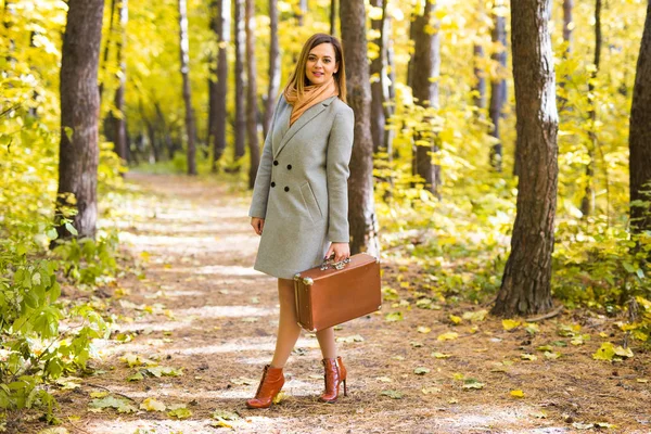 Herfst, seizoen en mensen concept - jonge vrouw met retro koffer in herfst park — Stockfoto