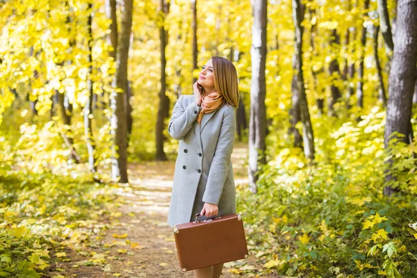 Estação, natureza e conceito de pessoas - mulher no parque de outono posando com mala — Fotografia de Stock