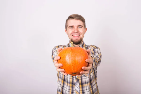 Retrato de un granjero divertido sosteniendo una calabaza en un estudio de fondo claro — Foto de Stock