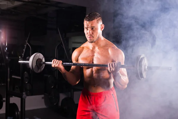 Muskulöser junger Mann stemmt Gewichte im Fitnessstudio — Stockfoto