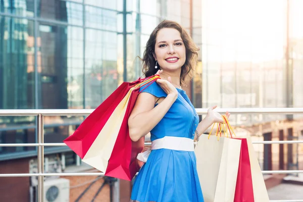 Einkauf, Rabatt- und Personenkonzept - Porträt einer jungen Frau im Kleid, die mit bunten Einkaufstaschen spaziert — Stockfoto