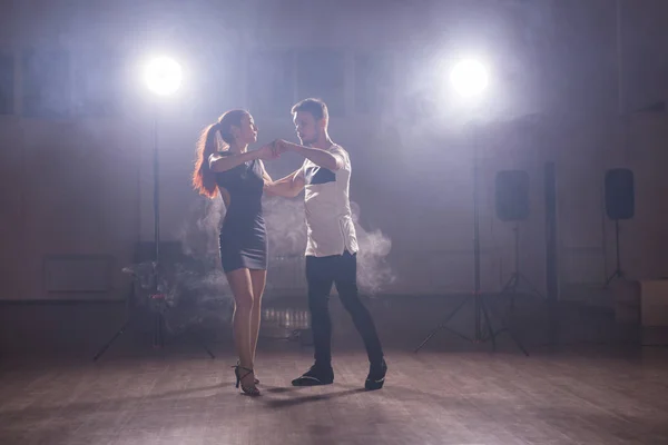 Dançarinos habilidosos se apresentando na sala escura sob a luz do concerto e fumaça. Casal sensual realizando uma dança contemporânea artística e emocional — Fotografia de Stock