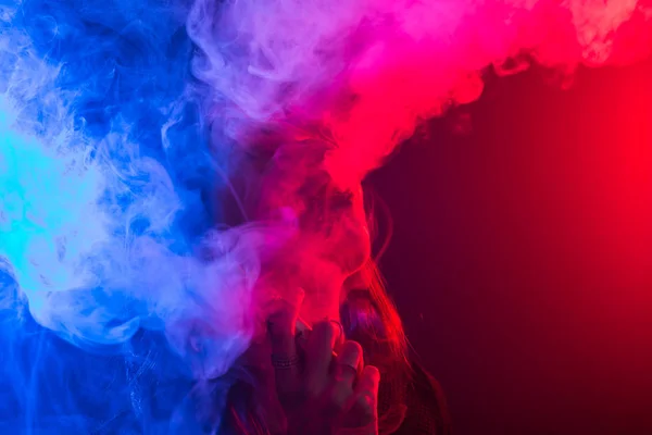 Portrait de jeune femme en néon rouge et bleu fumée avec vape ou e-cigarettes — Photo