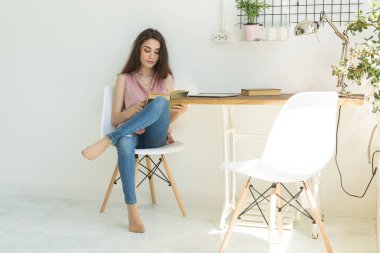 Eğitim ve insan kavramı - kitap ile sandalye üzerinde oturan genç kadın