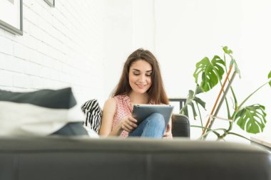 Teknolojileri, iletişim, kadın kanepede oturan ve tablet sohbet ve gülümseyen kavramı - genç insanlar