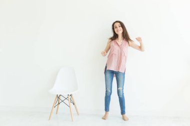 Duygu ve insanlar kavramı - beyaz sandalyeyi yanına dans ve beyaz arka plan üzerinde gülümseyen genç kadın