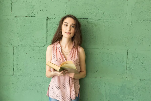 Література, освіта, концепція людей - студентка читає книгу над зеленою стіною — стокове фото