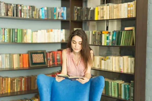 Persone, istruzione e concetto universitario - giovane studentessa con un libro in biblioteca — Foto Stock