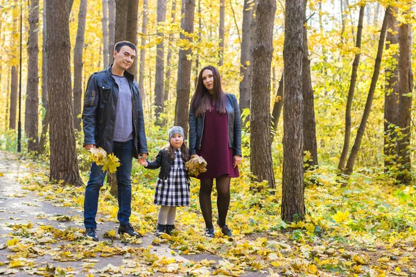Pessoas, família e conceito de lazer - família feliz com a filha andando no parque de outono — Fotografia de Stock