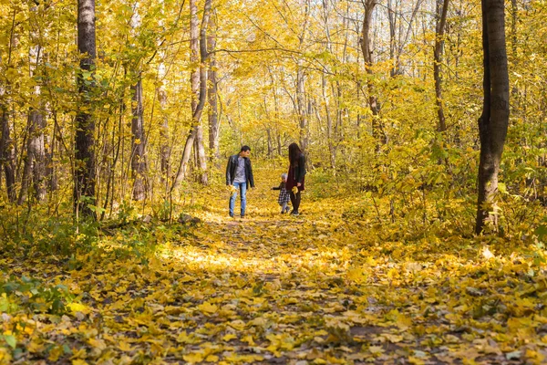Família, outono, conceito de pessoas - jovem família caminhando no parque no dia de outono — Fotografia de Stock