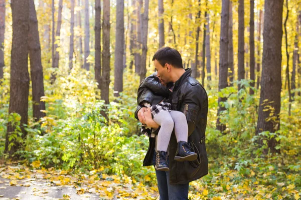 Paternidad, familia y concepto de ocio - padre sosteniendo a su pequeña hija en sus brazos en el parque de otoño — Foto de Stock