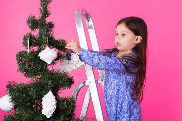 Christmas, childhood and people concept - little girl standing on step-ladder decorating the christmas tree — Stock Photo, Image