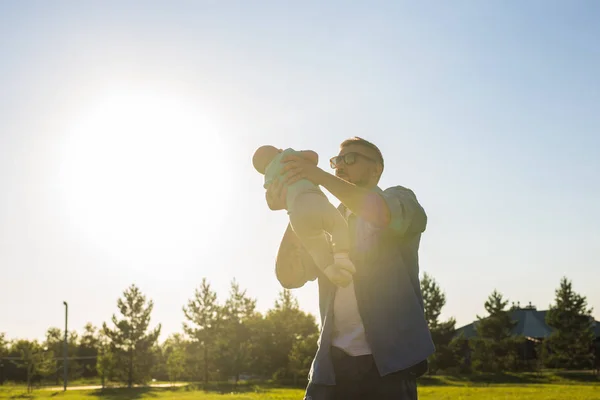 Happy father holding baby son, throwing baby in air. Concept of happy family, fathers day and child. — Stock Photo, Image