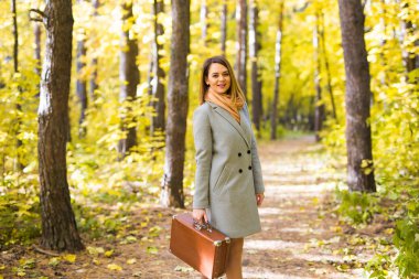 Sonbahar, Doğa ve insan kavramı - kahverengi çanta sonbaharda yürüyüş güzel gülümseyen kadın portresi