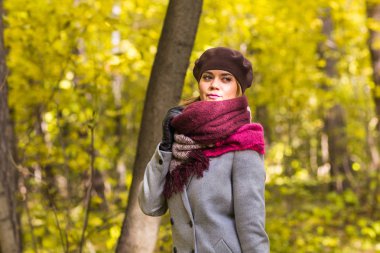 Sonbahar, Doğa, insanlar kavramı - gri bir ceket ve parkta duran bir bere güzel genç kadın.