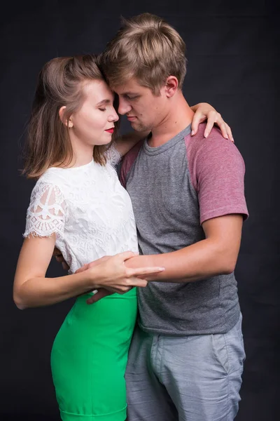 Bonito jovem casal abraçando e beijando isolado no fundo preto . — Fotografia de Stock