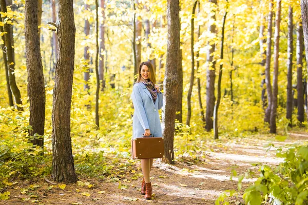Menschen, Jahreszeit und Naturkonzept - junge Frau spaziert mit Koffer durch Herbstpark — Stockfoto