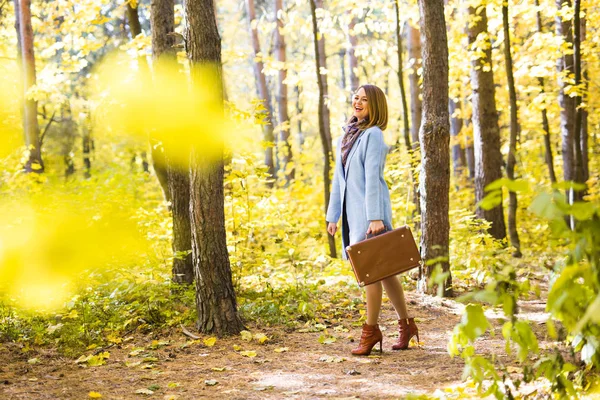 Outono, natureza e conceito de pessoas - Jovem mulher bonita andando no parque com mala — Fotografia de Stock