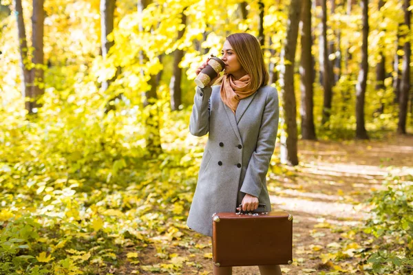 Pessoas, estação e conceito de moda - jovem mulher bebendo café no parque de outono — Fotografia de Stock