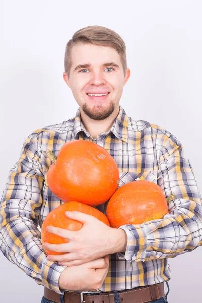 Personas, vacaciones y el concepto de otoño - hombre guapo con calabazas en el fondo blanco — Foto de Stock