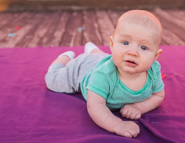 Niño lindo bebé acostado en la manta en el día de verano en la naturaleza. Picnic familiar en un parque . — Foto de Stock