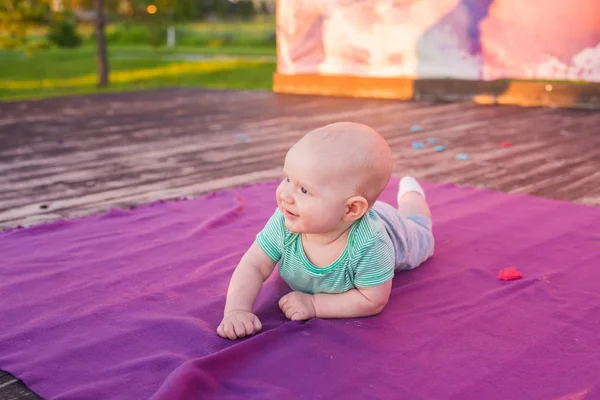 Милый мальчик лежит на одеяле в летний день на природе. Семейный пикник в парке . — стоковое фото