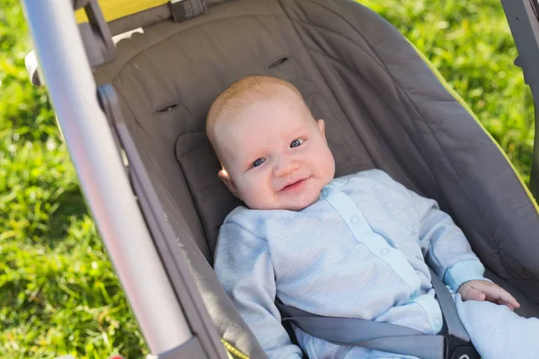 Adorable niño sentado en el cochecito y sonriendo — Foto de Stock