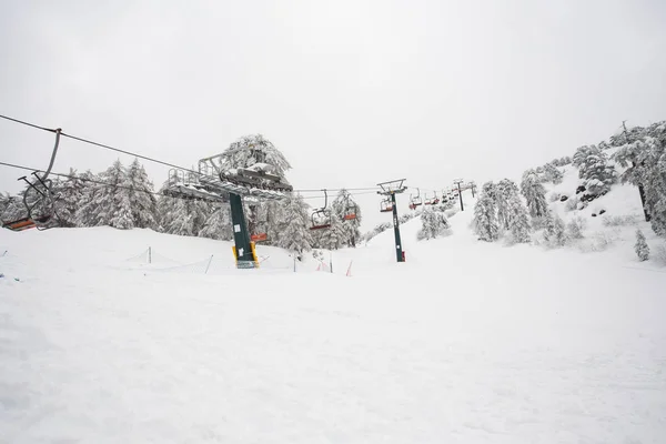 Λιφτ του σκι και το τελεφερίκ που ανεβαίνει το βουνό φέρνοντας snowboarders στις πίστες σκι. — Φωτογραφία Αρχείου