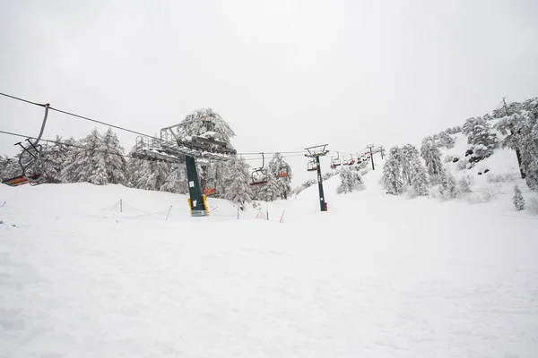 Ski lifts and cable cars going up the mountain bringing snowboarders to ski slopes. — Stock Photo, Image