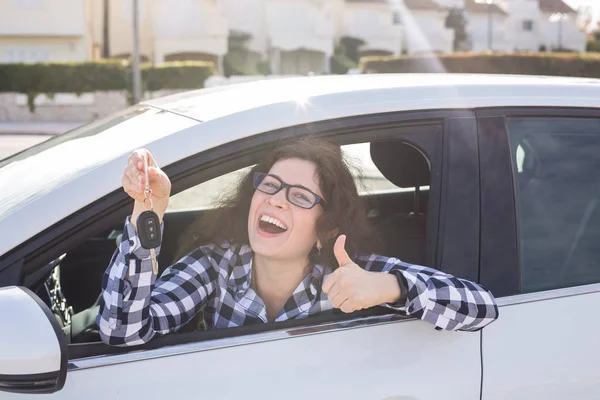 Mujer joven en el coche muestra los pulgares hacia arriba y la clave — Foto de Stock