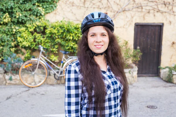 Χαμογελαστή γυναίκα με κράνος θέση στο παρασκήνιο ποδήλατο και σοκάκι — Φωτογραφία Αρχείου