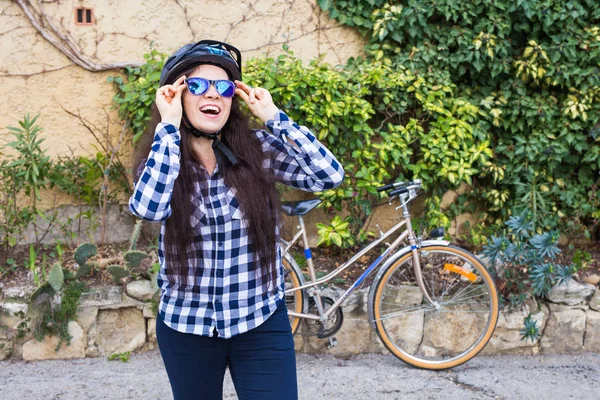 Красивая женщина в шлеме надеть солнцезащитные очки на заднем плане велосипед и улицу — стоковое фото