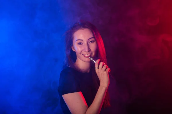 Портрет женщины в цветном неоновом дыме с парой или электронной сигаретой . — стоковое фото