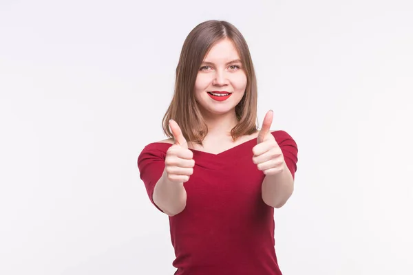 Joven mujer positiva mostrando pulgares hacia arriba sonriendo sobre fondo blanco — Foto de Stock