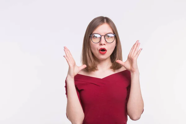 Moda, expresión y concepto de personas - mujer joven en gafas sorprendida y con las manos en alto sobre fondo blanco — Foto de Stock