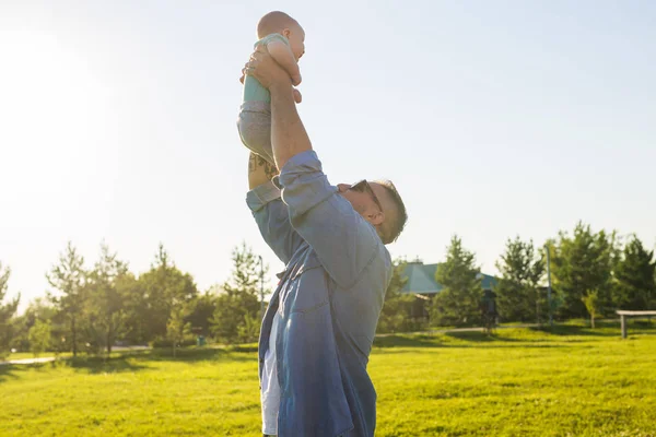 Heureux père tenant bébé fils, jetant bébé dans l'air. Concept de famille heureuse, fête des pères et des enfants . — Photo