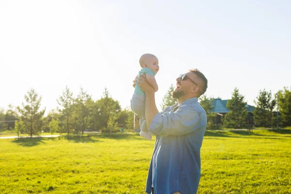 Happy father holding baby son, throwing baby in air. Concept of happy family, fathers day and child. — Stock Photo, Image