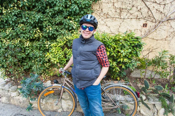 Bonito ciclista cara em roupas de ciclismo e capacete posando perto de bicicleta olhando para a câmera, sorrindo — Fotografia de Stock