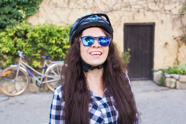 Ευτυχισμένη γυναίκα με κράνος και γυαλιά ηλίου θέτοντας βάθους ποδηλάτων και δρόμο — Φωτογραφία Αρχείου