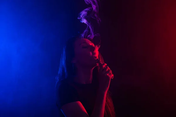 Młoda kobieta palenia vape lub e papieros w neon light — Zdjęcie stockowe