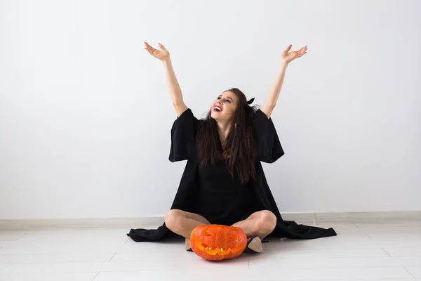 Femme gothique mignonne dans des vêtements de style halloween avec citrouille dans les mains — Photo