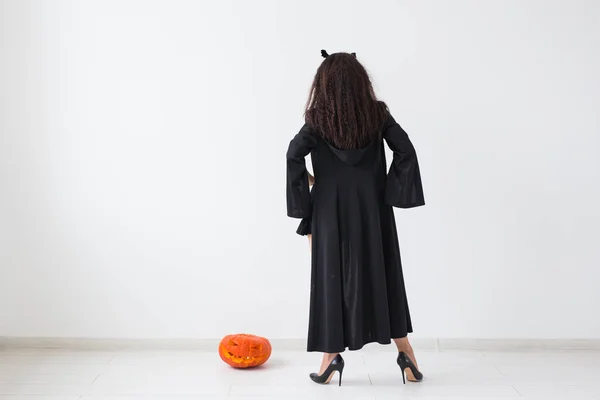 Retrato de uma mulher morena elegante com abóbora halloween sobre fundo claro com espaço de cópia — Fotografia de Stock