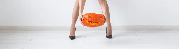 Close up of hands holding carved pumpkin over light background with copy space — Stock Photo, Image