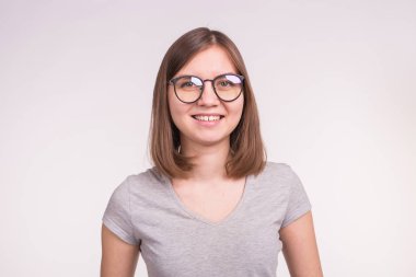 Bir gözlük kısa kahverengi saçlı beyaz genç kadın portresi.