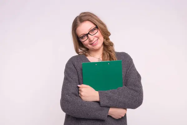 Porträt einer ruhigen, smarten jungen Frau mit grünem Papierordner auf weißem Hintergrund — Stockfoto